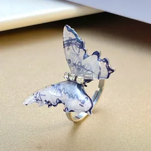 Macro shot of silver butterfly ring with blue ink texture wings and sparkling crystals