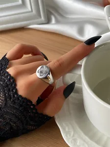 Detail of silver signet ring featuring a black butterfly engraving on a round disk