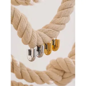 Minimalist geometric U-shape titanium earrings in gold and silver hanging on a rustic rope