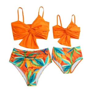 Costumi da bagno coordinati mamma e figlia con top arancioni e slip a stampa tropicale