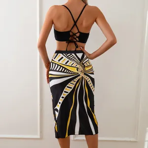 Three-piece bikini set featuring backless black top and high waist geometric print skirt