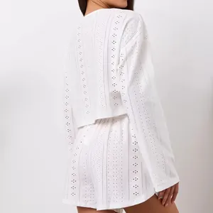 Detail of white long-sleeved eyelet embroidery set showing delicate geometric cut-outs