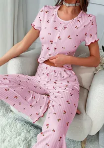 Detailed view of pink pajama set featuring cherry prints and red lettuce edge trimmings