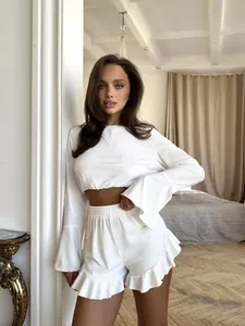 Detail of white lounge set with ribbed texture, ruffled hem shorts, and flared long sleeves