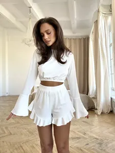 Close-up of white ribbed fabric set featuring flare sleeves and ruffled shorts