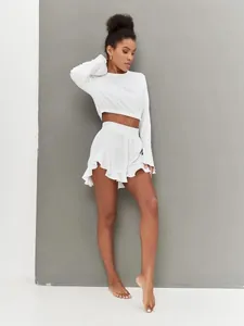 Detail of ribbed knit fabric texture on white long sleeve crop top and ruffled hem shorts