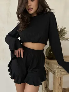 Detail of black ribbed lounge set featuring flared sleeves and ruffled shorts hem