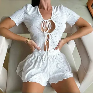 Detail view of white eyelet embroidery on a short-sleeve lace-up top and scalloped shorts set