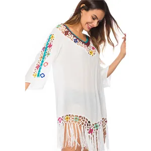 Close-up of white crochet beach cover-up featuring colorful knit rings and long fringes