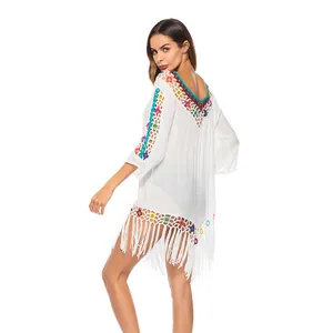 Detail of white crochet beach cover-up with colorful flower patterns and long tassels