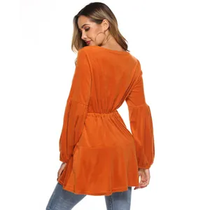 Orange long sleeve velvet top with V-back design and ruffled hem on model