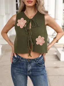 Détails de maille d'un gilet vert court avec broderies florales roses et liens frontaux