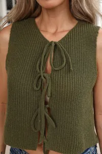 Dettaglio ravvicinato del gilet in maglia verde militare con lacci a fiocco sul davanti