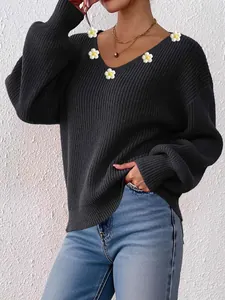 Détail du pull à col en V montrant les accents floraux au crochet et la maille