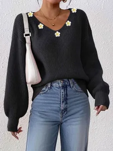 Détail d'un pull noir à col en V avec fleurs au crochet et poignets côtelés