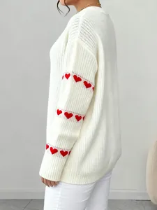Dettaglio del maglione bianco in maglia con ricami a forma di cuore rosso sulle maniche