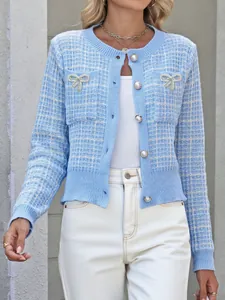 Details der hellblauen Strickjacke mit Perlenknöpfen und glitzernden Schleifen