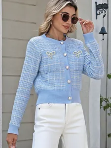 Details der hellblauen Strickjacke mit Pailletten-Schleifen und Perlenknöpfen auf Tweed