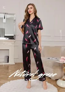 Detail of premium black silk pajamas with pink feather print and soft satin texture