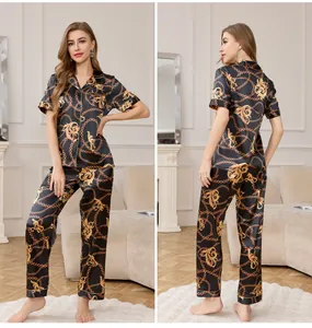 Detail of premium black silk pajama set with gold chain print and baroque floral patterns