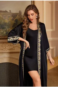 Detailed close-up of luxurious black satin robe featuring elegant gold baroque print edges