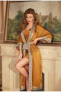 Detail of elegant gold satin robe set with geometric patterned trim and silk finish