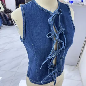Dettaglio dell'allacciatura incrociata traforata sul gilet di jeans blu scuro