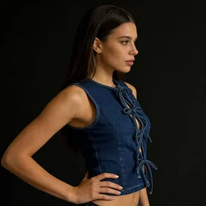 Détail du gilet en jean bleu foncé avec lacets à nœuds chic et tissu en denim texturé