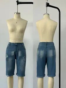 Detail of distressed blue denim shorts with ripped design and rolled cuffs on a mannequin