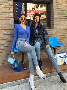 Détail d'un jean skinny gris associé à un haut bleu à manches longues et col en V