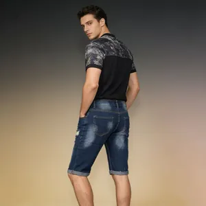 Rear view of men's distressed denim shorts with ripped details and roll-up hem design