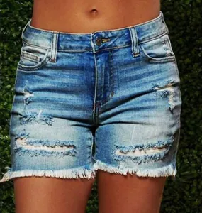 Detail of light blue denim shorts featuring distressed ripped holes and frayed fringe hemline
