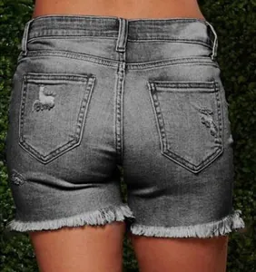 Detail of distressed denim shorts showing ripped texture and frayed hem on back pockets