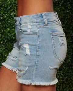 Close-up of light blue denim shorts featuring distressed ripped details and frayed tassels