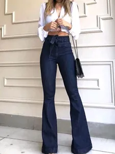 Detail of high waist dark blue flare jeans with a stylish matching waist tie belt