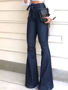 Detail of high waisted dark blue denim flare jeans with matching fabric bow belt