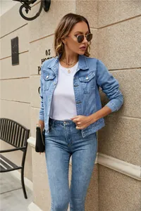 Detail of light blue denim jacket showing metal buttons and lapel collar design