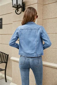 Detail view of the vertical stitching and adjustable metal buckles on light blue denim jacket