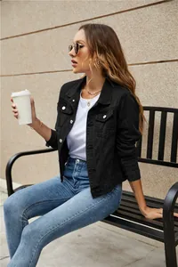 Close-up of black slim fit denim jacket with silver buttons and chest flap pockets
