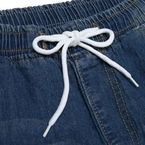 Detailansicht des elastischen Bundes mit weißem Kordelzug und gelben Nähten an blauer Jeans