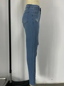 Détail du jean bleu clair délavé avec trous usés et coupe ajustée sur un mannequin