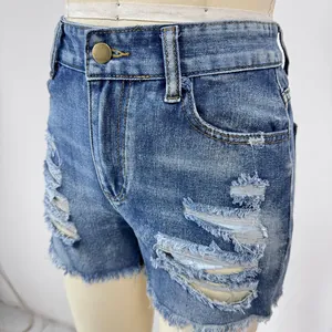 Detail of high-waisted blue denim shorts featuring distressed rips and raw hem edges