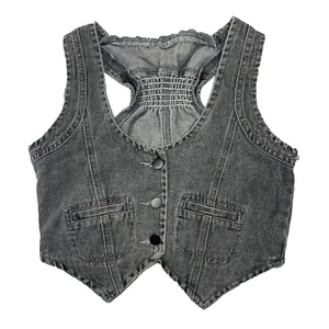 Dettaglio macro di un gilet in denim grigio scuro con taglio vogatore e arricciatura