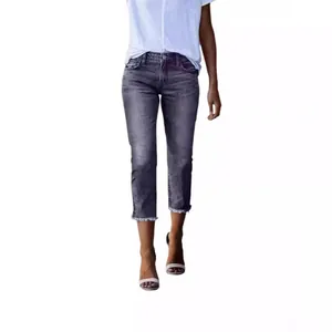 Detail view of frayed hem on dark grey slim-fit cropped denim jeans for women