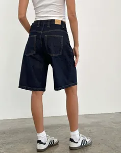 Detalle de los bermudas de mezclilla azul oscuro con costuras en contraste y parche de cuero