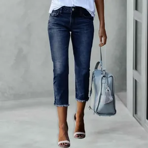 Detail view of dark blue cropped slim-fit jeans with frayed hems and street style look