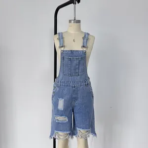 Macro detail of distressed denim overalls with ripped holes and adjustable metal buckles