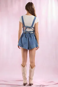 Back view of women's denim overalls with decorative bow ties and a white ribbed t-shirt