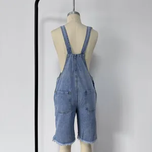 Detail view of denim overalls featuring back pockets and distressed raw hem edges