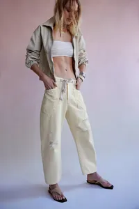 Détail du pantalon droit crème avec cordon de serrage et finitions usées élégantes